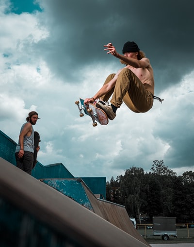 Wear a hat, a man dressed in brown pants with skateboard jumps
